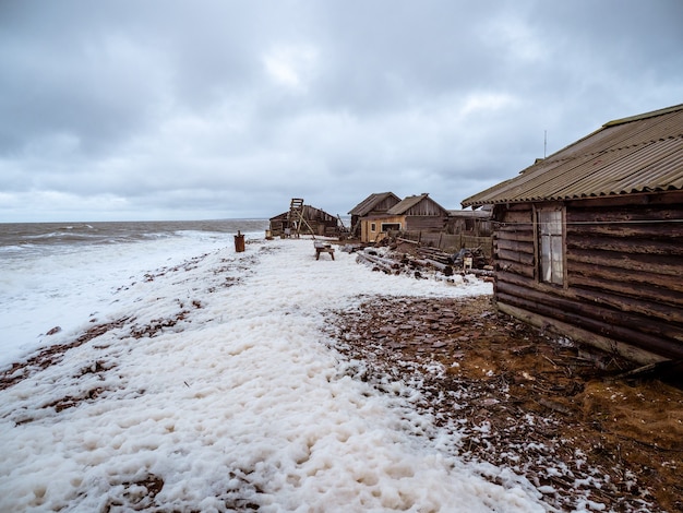 Фото Драматический морской пейзаж с бушующим белым морем и рыбацкой хижиной на берегу. кандалакшский залив. умба. россия.