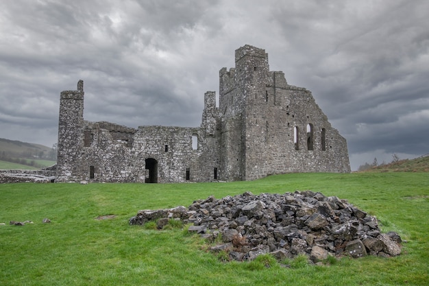 Il drammatico cielo sopra fore abbey con un mucchio di pietre in primo piano