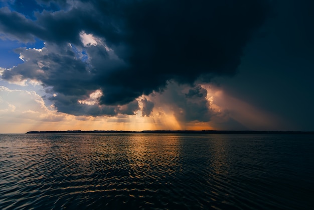 Dramatic sky with clouds and sun rays over river in summer cloudy