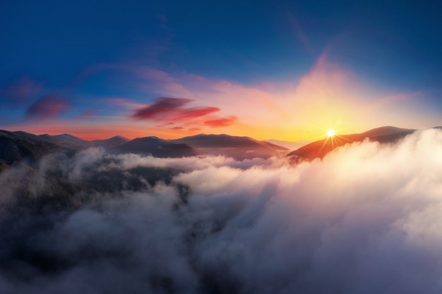 山の雲の上の劇的な夕日