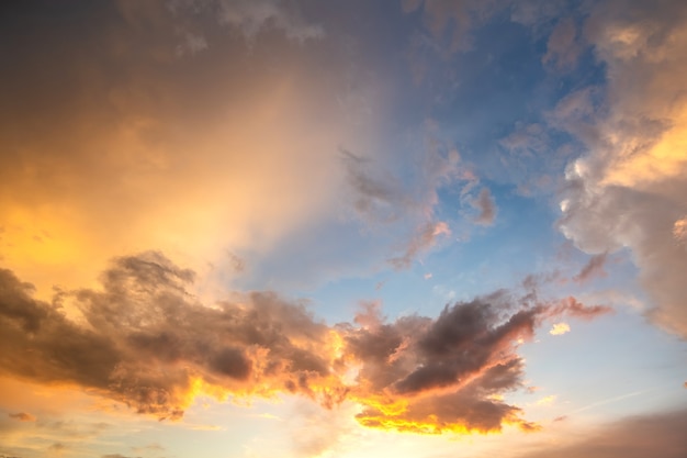 Foto drammatico paesaggio del cielo al tramonto con nuvole gonfie illuminate dal sole al tramonto arancione e cieli blu.