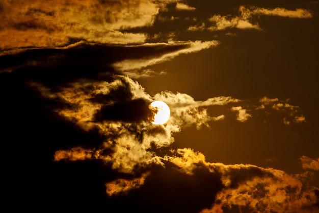 구름과 극적인 일몰입니다. 둥근 태양이 앉습니다.