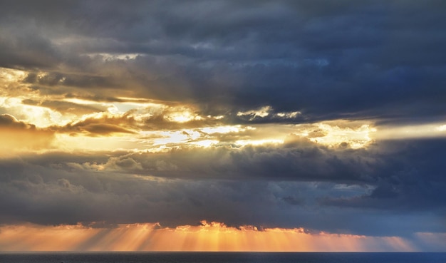 Dramatic thunderclouds over mediterranean sea with sun rays breaking through