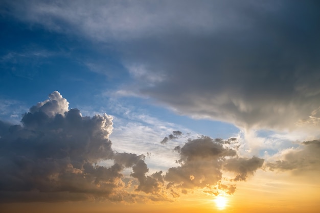 オレンジ色の夕日と青い空に照らされたふくらんでいる雲と劇的な黄色の夕日の風景。