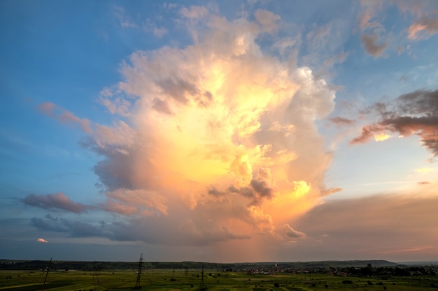 Dramatic yellow sunset over rural area with stormy puffy clouds