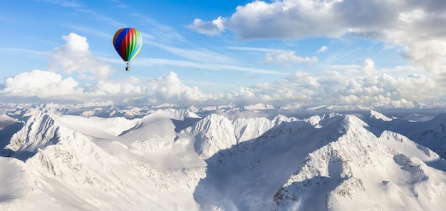 Dramatisch berglandschap bedekt met wolken en heteluchtballonvliegen