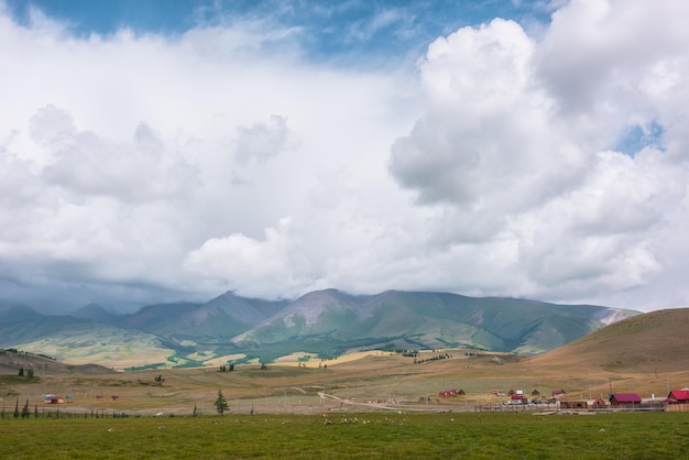 Dramatisch berglandschap met zonovergoten groene hoge bergketen onder grijze, regenachtige lage wolken Prachtig berglandschap met contrast van licht en schaduw bij veranderlijk weer Bewolkt in de bergen