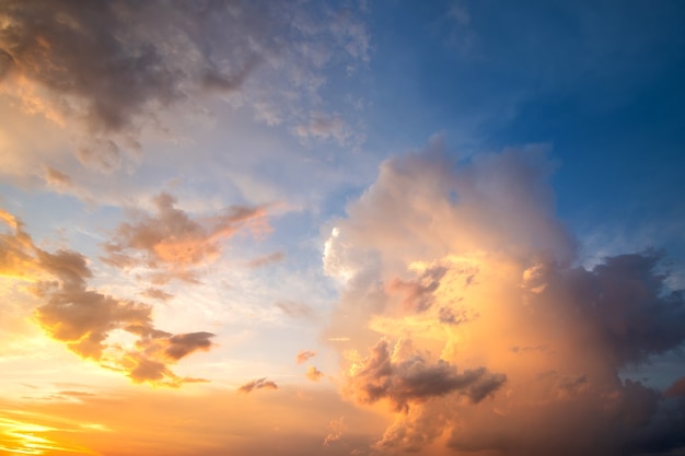 Foto dramatisch bewolkt zonsonderganglandschap met gezwollen wolken die door oranje ondergaande zon en blauwe hemel worden verlicht.