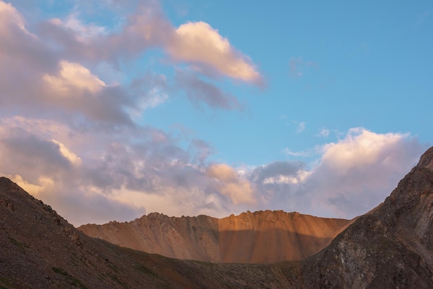 Dramatisch landschap met zonovergoten brede scherpe bergkam onder wolken in zonsondergangkleuren bij wisselvallig weer Sfeervol berglandschap met grote scherpe rotsen op de bergkam onder bewolkte zonsonderganghemel