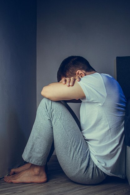 Dramatisch levensstijlportret van een knappe man van in de dertig en veertig die verdrietig op het bed zit, zich angstig voelt en lijdt aan een depressie Aantrekkelijke depressieve en overstuur man in de slaapkamer thuis