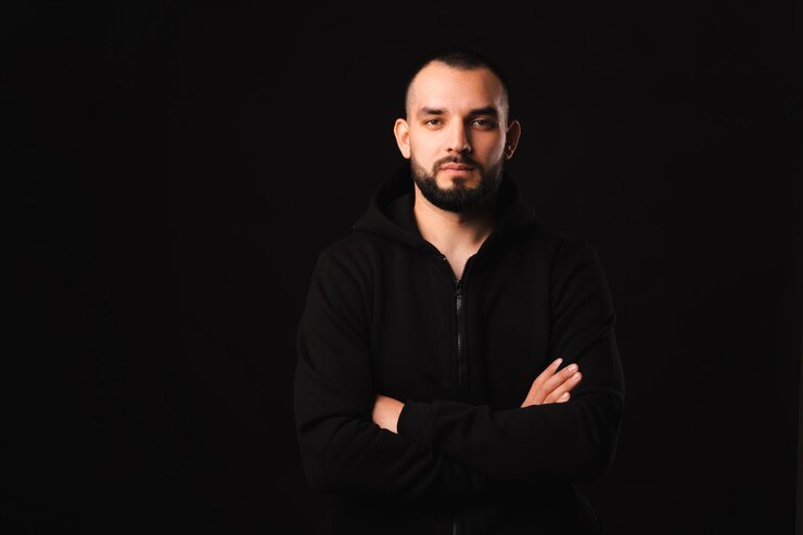 Dramatisch portret van een sterke jonge man in het zwart met gekruiste armen