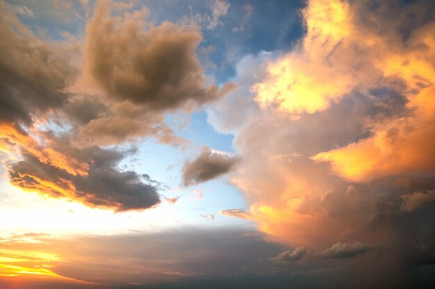 Dramatische hemel bij zonsondergang met gezwollen wolken verlicht door oranje ondergaande zon.