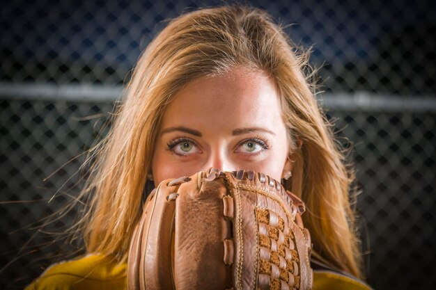 Foto dramatische jonge vrouw met softbalhandschoen die haar gezicht bedekt in de open lucht