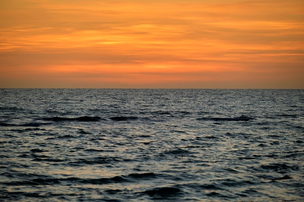 Dramatische rode oceaangolven bij zonsondergang met zacht avondzee donker water