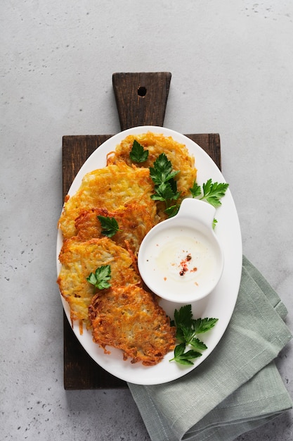 Draniki aardappelbeignets, vegetarische aardappelpannenkoekjes, geserveerd met verse kruiden en knoflookyoghurtsaus