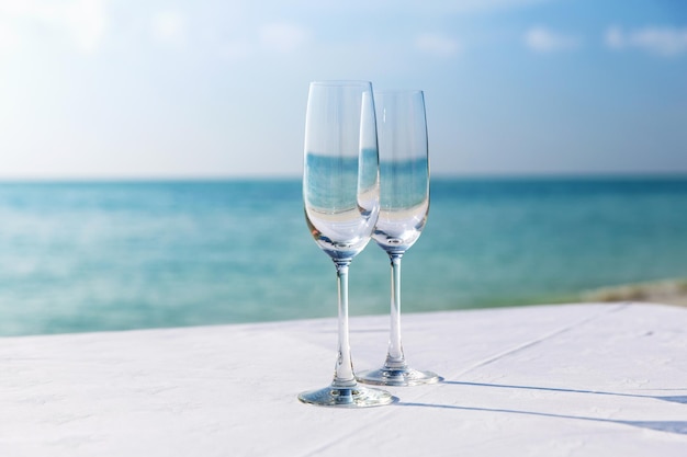 drank, vakantie, zomervakantie en feestconcept - close-up van twee champagneglazen op tafel over zee op het strand