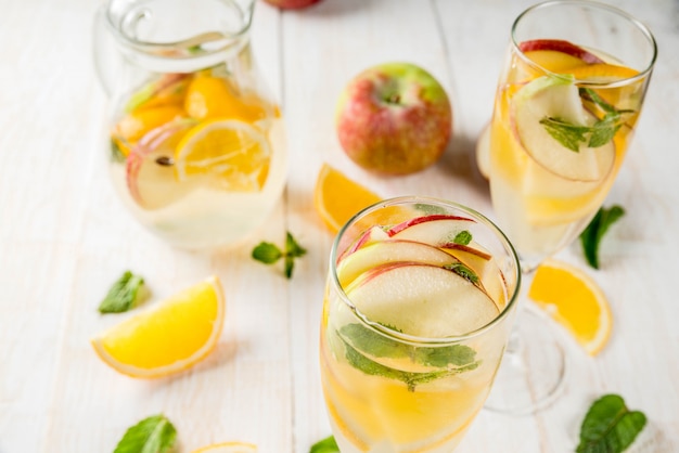 Drankjes en cocktails. Witte herfstsangria met appels, sinaasappel, munt en witte wijn