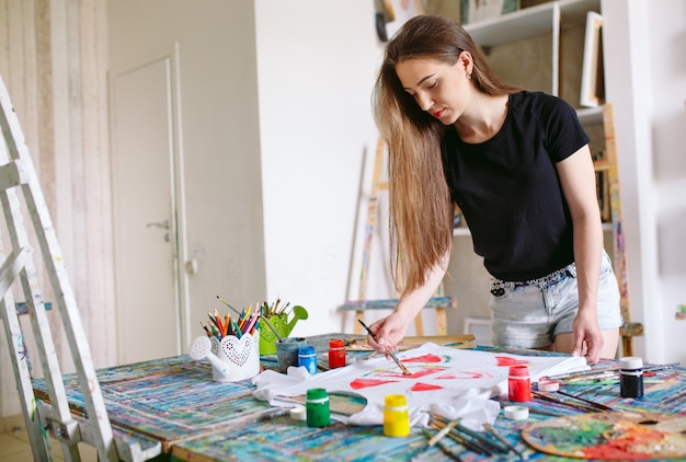 Drawing on clothes. Girl draws on a white T-shirt.