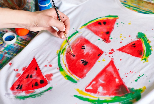 Drawing on clothes. Girl draws on a white T-shirt.