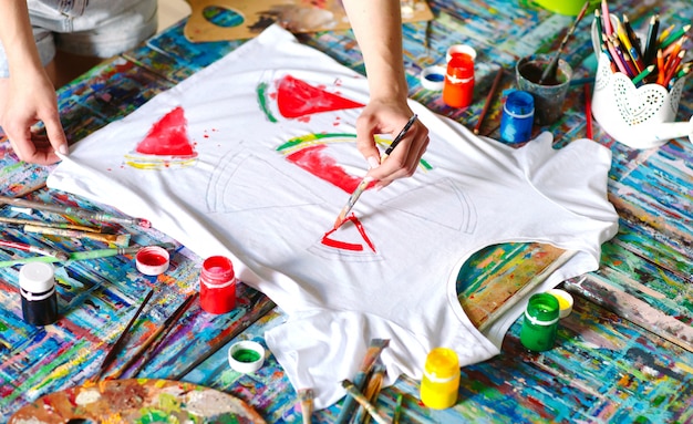 Drawing on clothes. Girl draws on a white T-shirt.