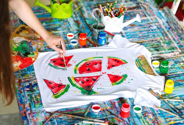 Drawing on clothes. Girl draws on a white T-shirt.