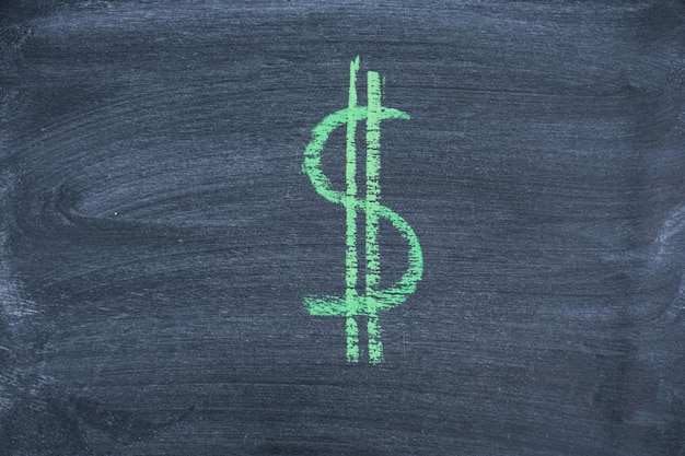 Photo drawing of the dollar symbol in green chalk on a black chalk board