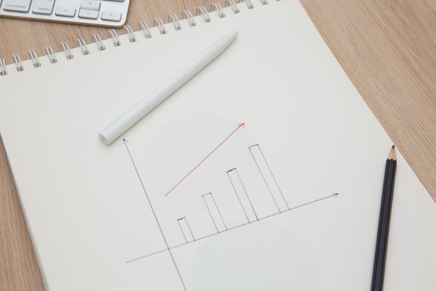 Drawing a graph of growth in a notebook on your desk at home.Wooden work table