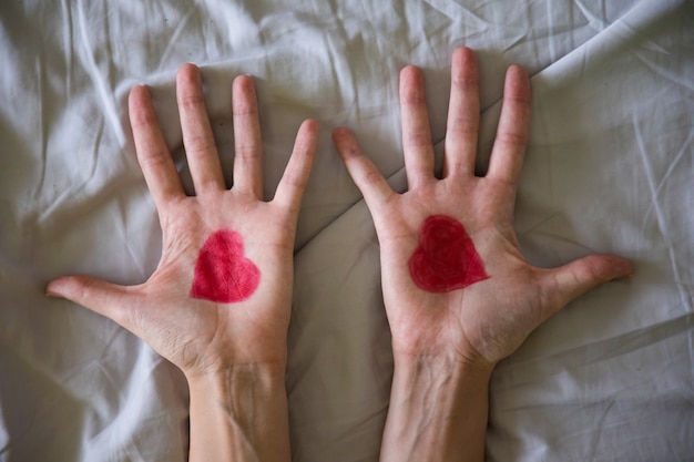 Drawing heart on hands of young woman