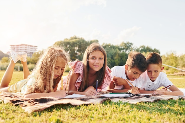 Drawing pictures Group of happy kids is outdoors on the sportive field at daytime