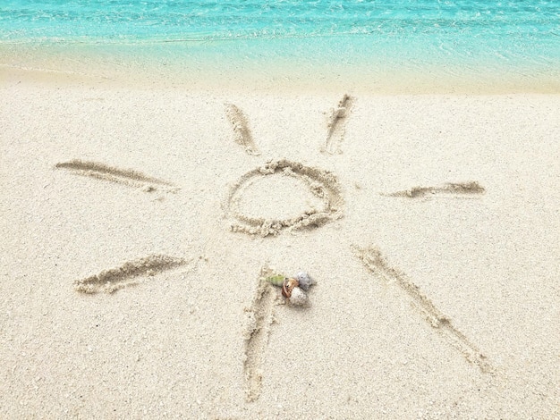사진 열대 섬 몰디브의 모래에 태양 그리기