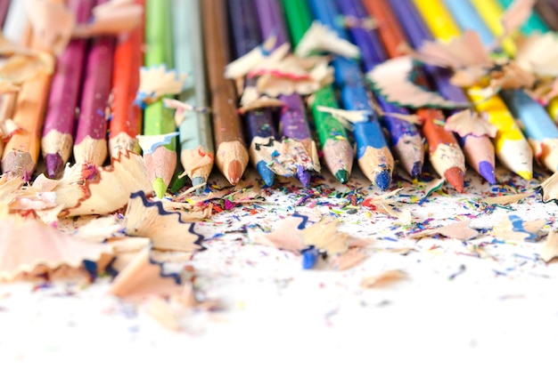 Photo drawing tools background. lot of colorful pencils frame with sawdust and shavings on white.