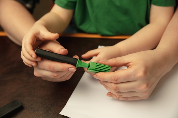 Disegnare con pennarelli colorati. immagine ravvicinata di mani femminili e bambini che fanno cose diverse insieme. famiglia, casa, istruzione, infanzia, concetto di beneficenza. madre e figlio o figlia, studiando.