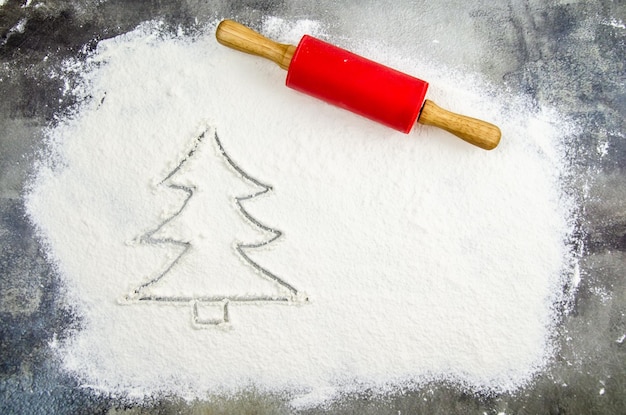 Drawn Christmas tree on flour scattered. Silhouette of Christmas tree made of flour, dark background