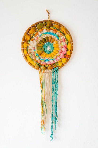 Dream catcher woven with wool on a white wall with copy space vertical picture