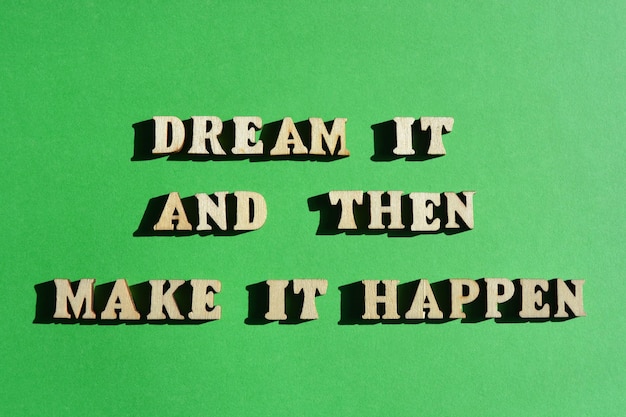 Photo dream it and then make it happen motivational words in wooden alphabet letters isolated on bright green background