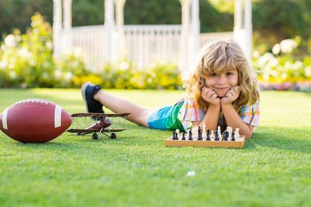 Dream kids and childhood concept child playing chess game in spring backyard laying on grass concent