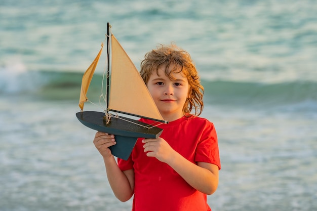 夏休みに海水でおもちゃのボートを持つ夏の子供の夢 おもちゃの seaili で遊ぶ小さな男の子