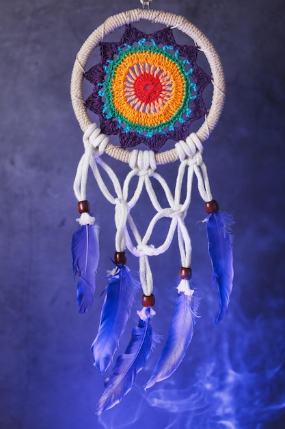 Dreamcatcher with multicolored weaving in blue smoke isolated on black