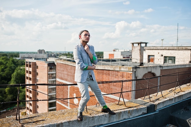 Dreamer stylish macho man in gray suit hat and glasses posed on the roof