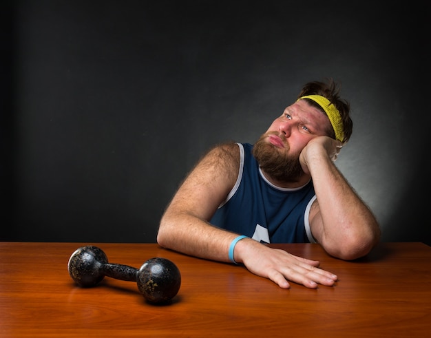 Dreaming man and a dumbbell at the table