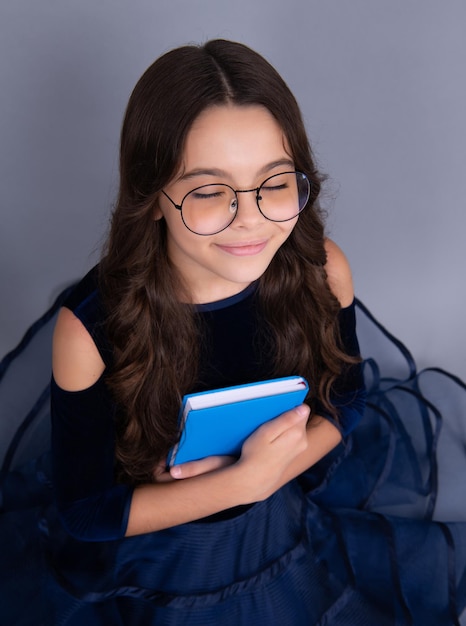 Dreaming schoolgirl in dress hold book and copybook ready to learn School children dream on isolated grey background