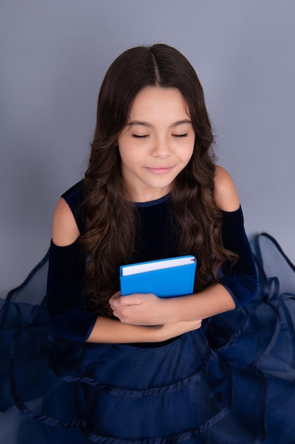 Dreaming schoolgirl in dress hold book and copybook ready to learn School children dream on isolated grey background