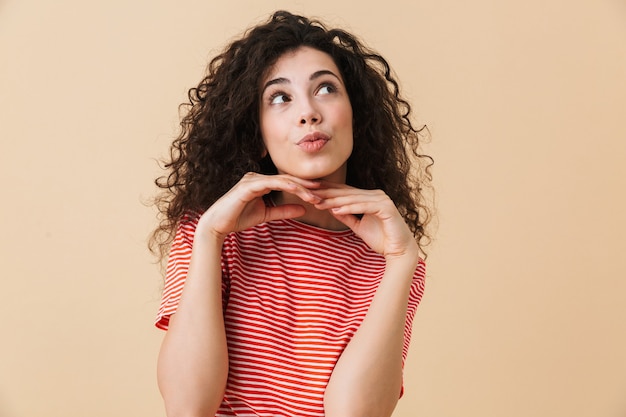 Dreaming young curly woman standing isolated