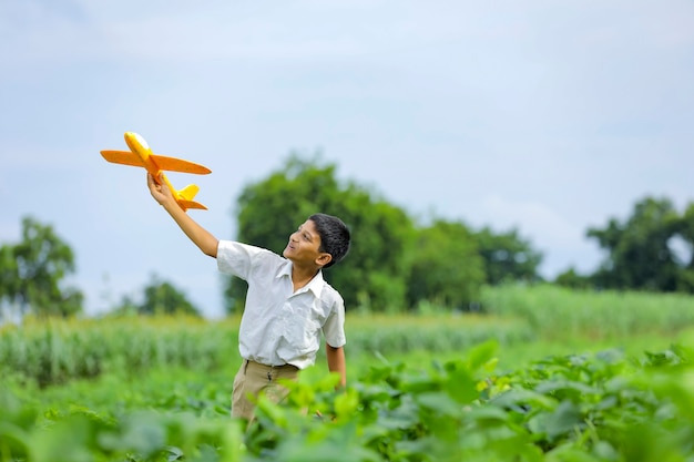 Dreams of flight! indian child playing with toy airplane at green field