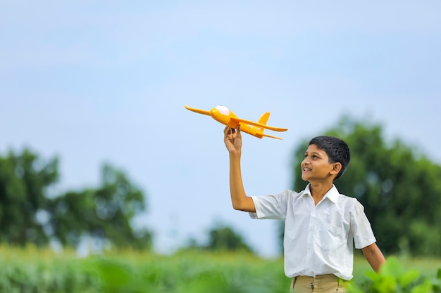 Sogni di volo! bambino indiano che gioca con aeroplano giocattolo al campo verde