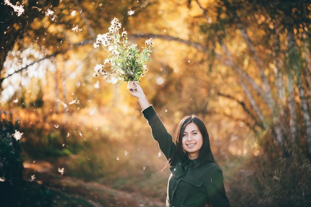 黄色の葉と背景のボケ味のアザミの花を持つ夢のような美しい少女。