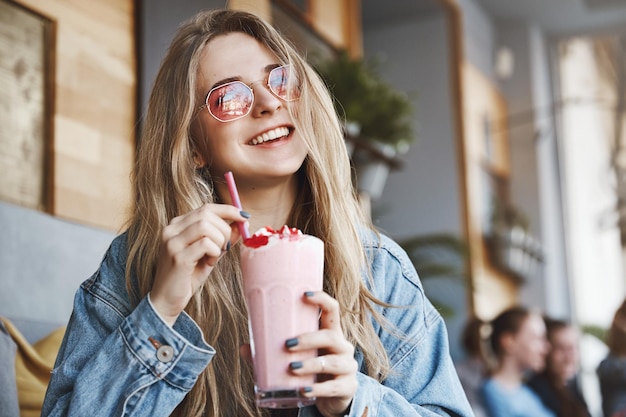 Donna europea sognante e spensierata con i capelli biondi in rosa sungl