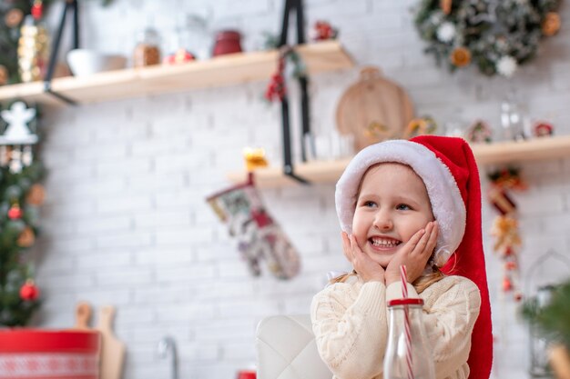 A dreamy child light sweater kitchen table smiling looks away.