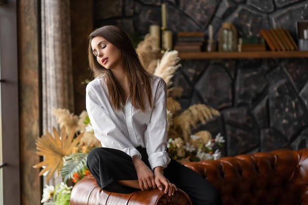 Photo dreamy girl sitting on the couch with her eyes closed