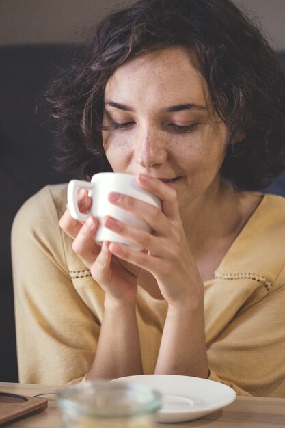 Ragazza sognante seduta con una tazza di caffè in mano